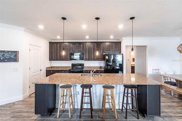 kitchen with a kitchen breakfast bar, an island with sink, and black appliances