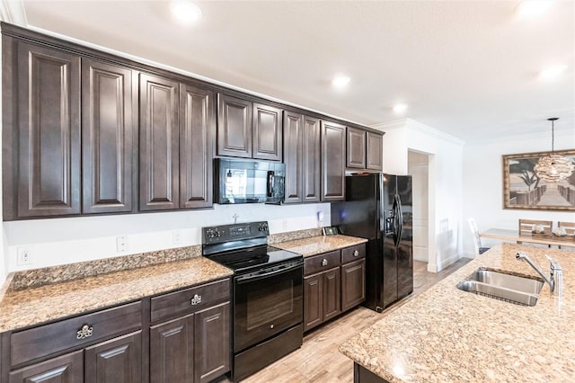 kitchen featuring pendant lighting, dark brown cabinetry, a sink, black appliances, and crown molding