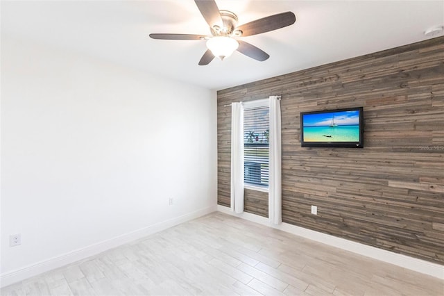 unfurnished room with an accent wall, ceiling fan, and baseboards