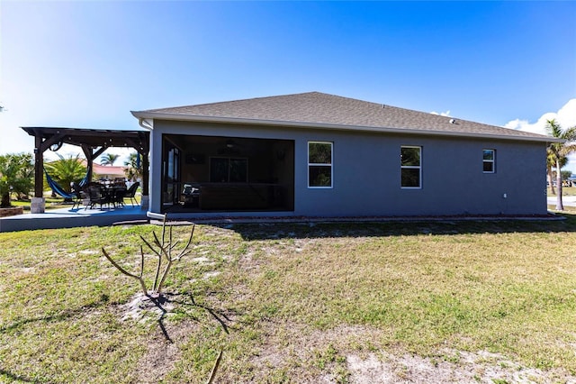 back of house with roof with shingles, a yard, a patio, stucco siding, and a pergola