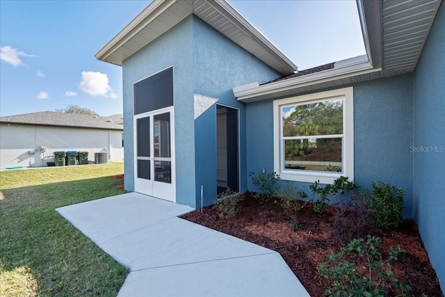 view of exterior entry with a yard and a patio area