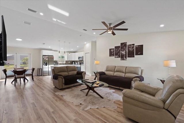 living room featuring vaulted ceiling, ceiling fan, and light wood-type flooring