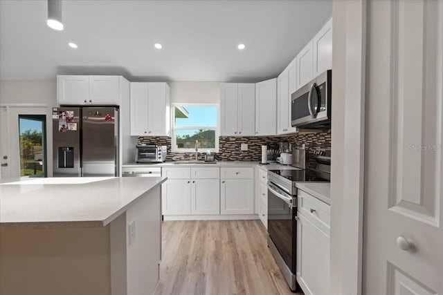 kitchen with appliances with stainless steel finishes, sink, decorative backsplash, and white cabinets