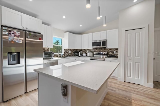 kitchen featuring pendant lighting, white cabinetry, stainless steel appliances, and a kitchen island