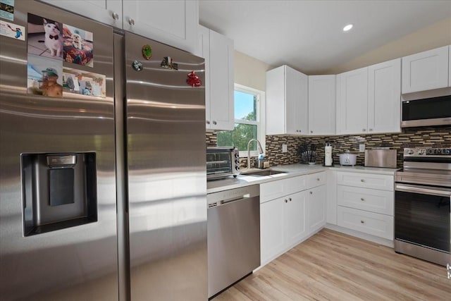 kitchen with white cabinetry, tasteful backsplash, stainless steel appliances, and vaulted ceiling