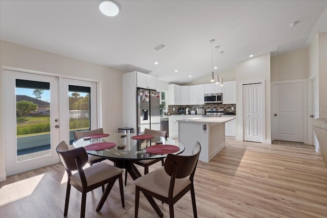 dining room featuring vaulted ceiling, light hardwood / wood-style flooring, and french doors