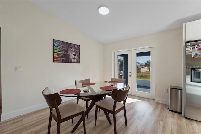 dining area with vaulted ceiling, french doors, and light wood-type flooring