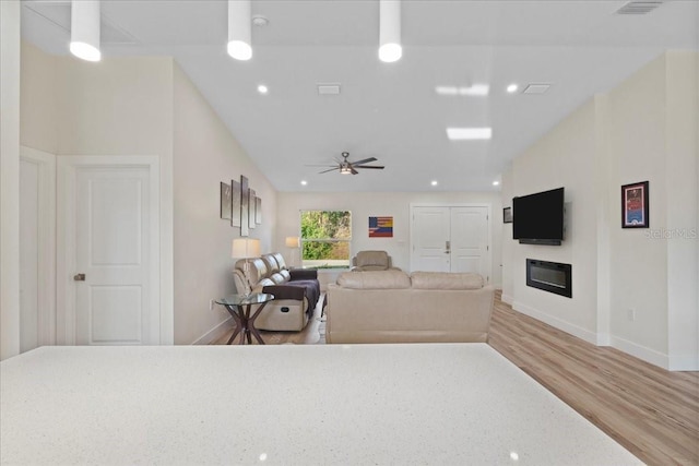 living room with lofted ceiling, ceiling fan, and light wood-type flooring