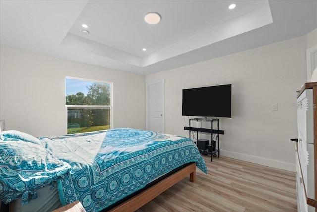 bedroom with a tray ceiling and light hardwood / wood-style floors