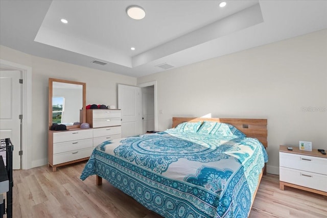 bedroom featuring light hardwood / wood-style flooring and a raised ceiling