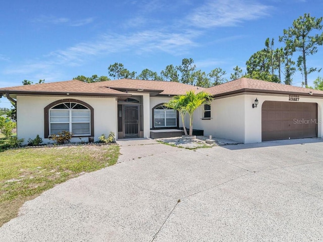 view of front facade with an attached garage, driveway, a front yard, and stucco siding