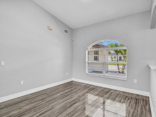 unfurnished room with baseboards, visible vents, and wood finished floors