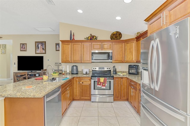 kitchen with sink, light stone counters, light tile patterned floors, kitchen peninsula, and stainless steel appliances