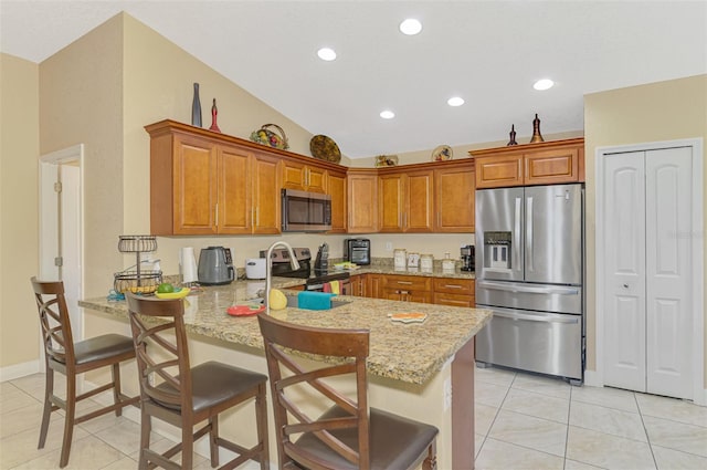 kitchen featuring light tile patterned floors, a breakfast bar, stainless steel appliances, light stone counters, and kitchen peninsula