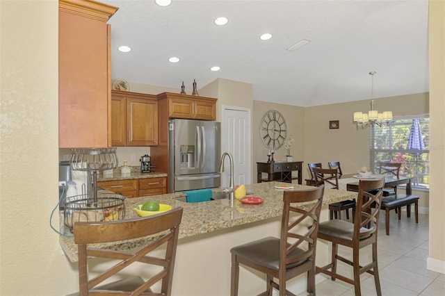 kitchen featuring sink, hanging light fixtures, light stone counters, kitchen peninsula, and stainless steel refrigerator with ice dispenser