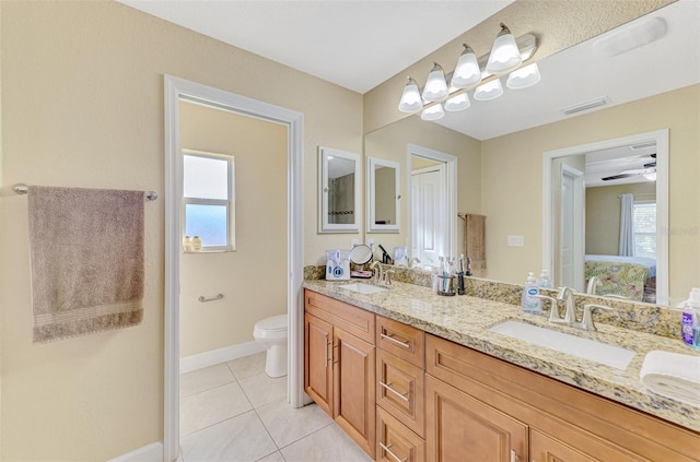 bathroom with vanity, a wealth of natural light, tile patterned floors, and toilet