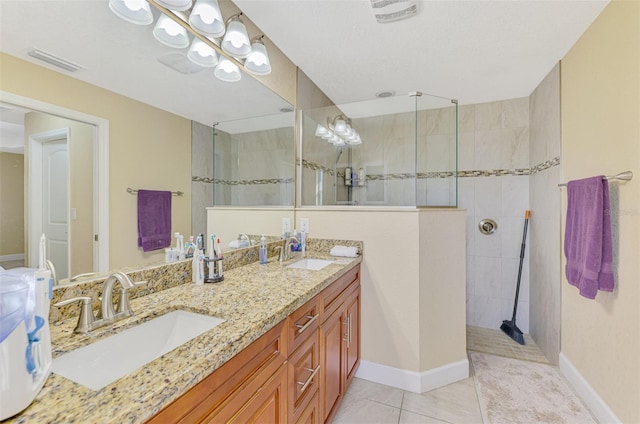 bathroom featuring a tile shower, vanity, tile patterned floors, and a textured ceiling