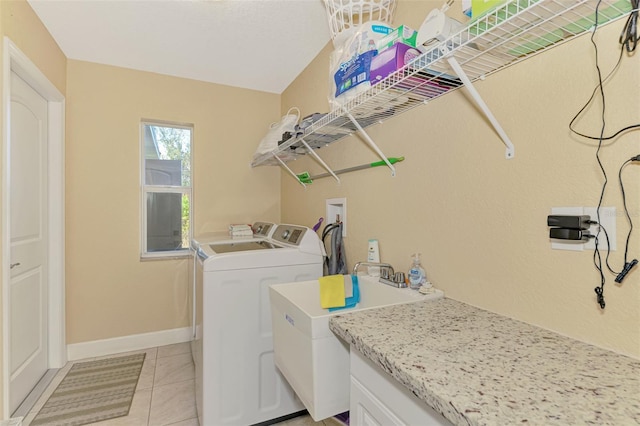 laundry area with light tile patterned flooring, washing machine and clothes dryer, and sink