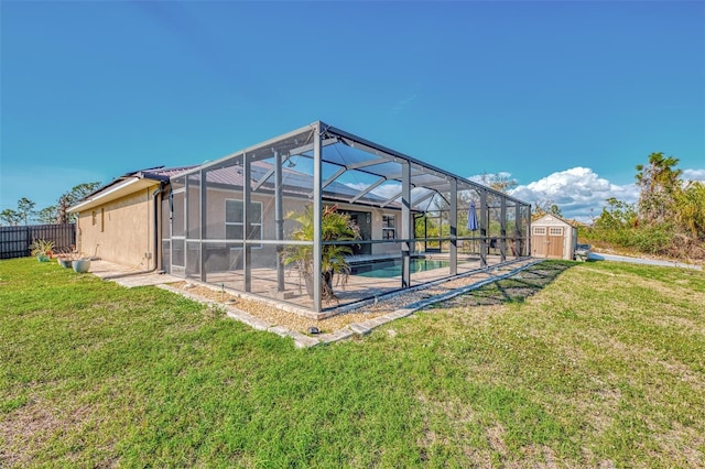 rear view of house with a storage shed, a yard, a patio, and glass enclosure