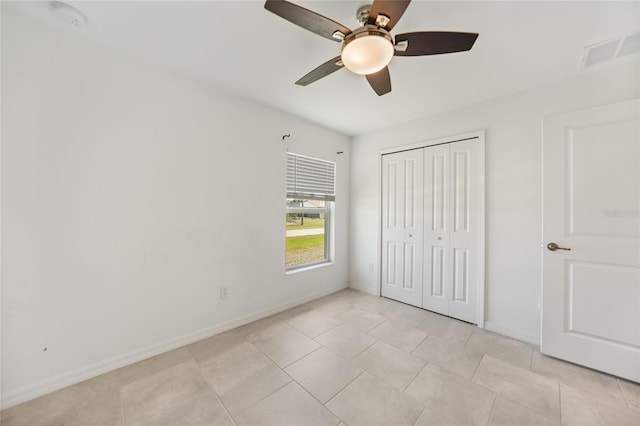 unfurnished bedroom with light tile patterned flooring, ceiling fan, and a closet