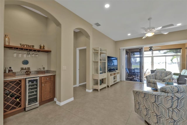 living room featuring ceiling fan, bar area, beverage cooler, and light tile patterned floors