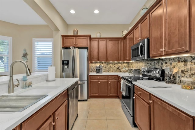 kitchen featuring backsplash, stainless steel appliances, light stone countertops, and light tile patterned floors