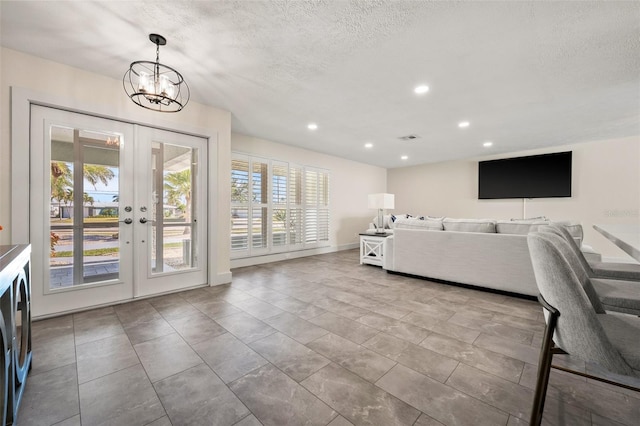 unfurnished living room featuring french doors, an inviting chandelier, a textured ceiling, and a wealth of natural light