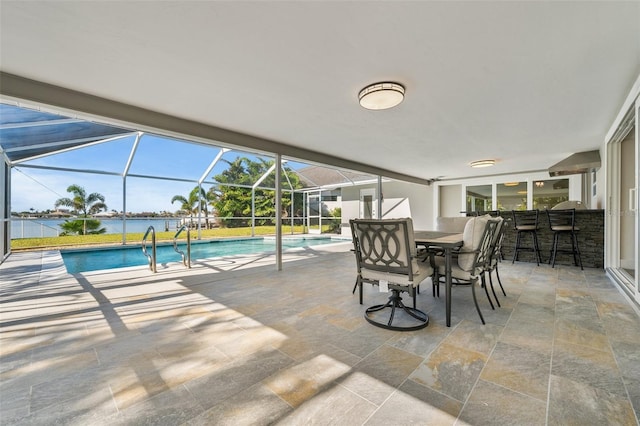 view of swimming pool featuring a patio, a water view, an outdoor bar, and glass enclosure