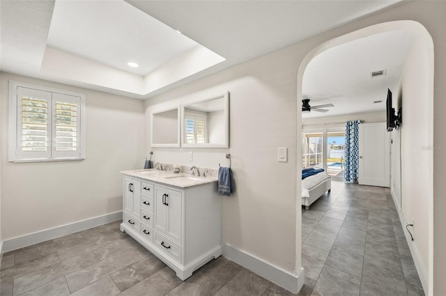 bathroom featuring ceiling fan, vanity, and a tray ceiling