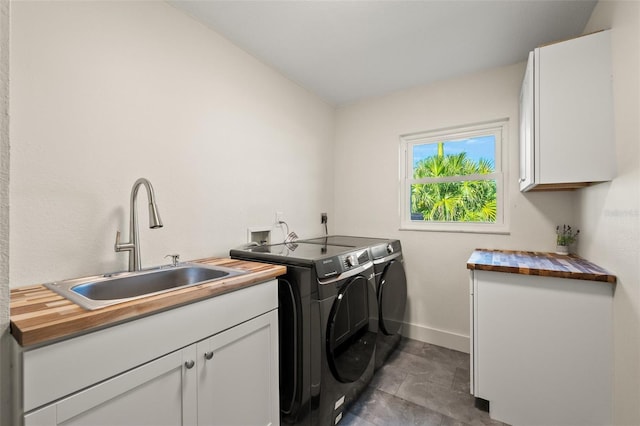 clothes washing area with cabinets, sink, and washer and dryer