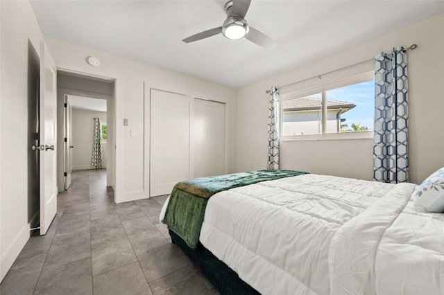 bedroom with ceiling fan, tile patterned floors, and a closet