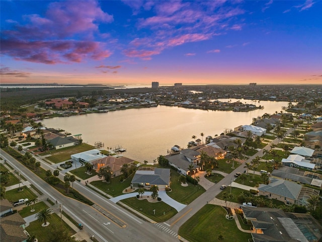 aerial view at dusk featuring a water view