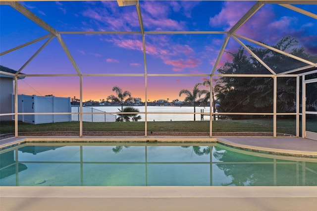 pool at dusk featuring a lanai and a patio area