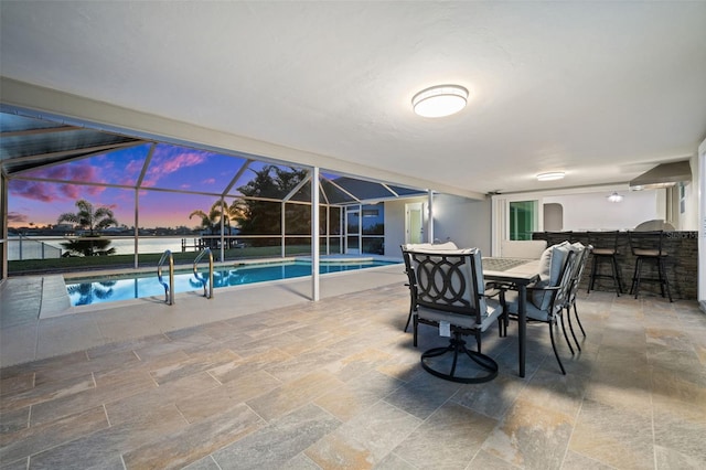 pool at dusk featuring a water view