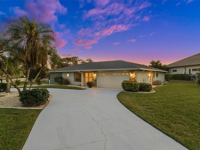 ranch-style home featuring cooling unit, a garage, and a lawn