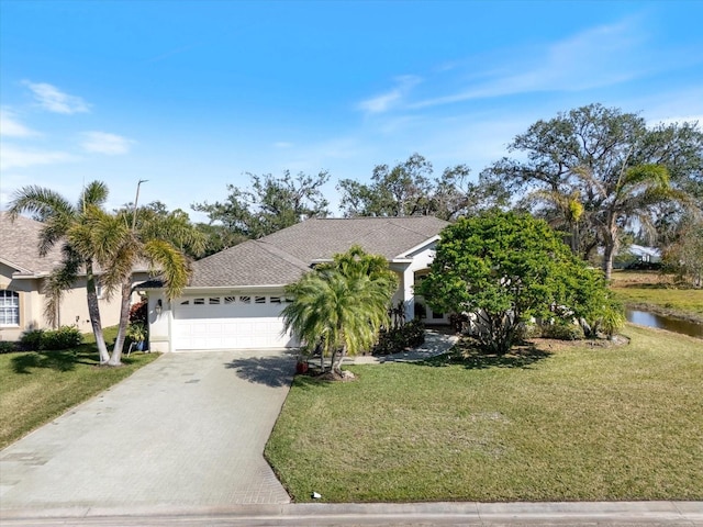 view of front of home with a garage, a water view, and a front lawn