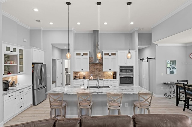 kitchen featuring pendant lighting, appliances with stainless steel finishes, a barn door, and white cabinets