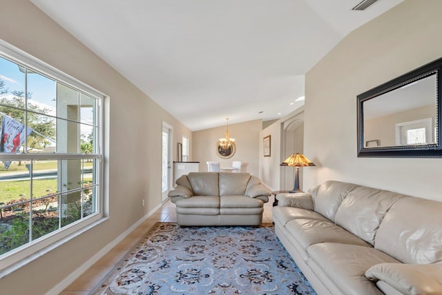 tiled living room with a healthy amount of sunlight, lofted ceiling, and a chandelier