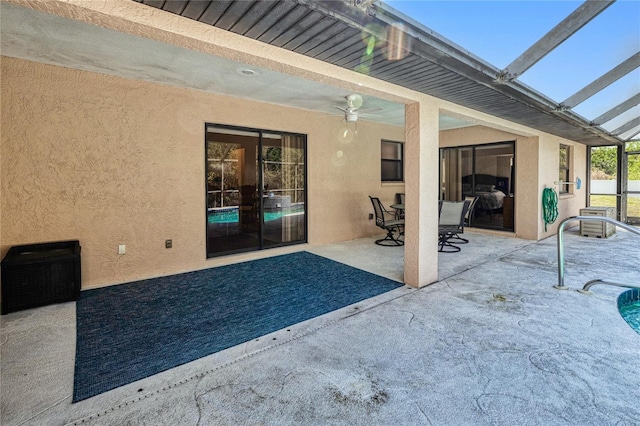 view of patio featuring ceiling fan and glass enclosure