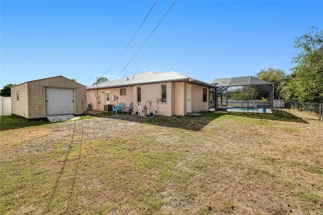 rear view of house with a fenced in pool, a lanai, a yard, and a shed