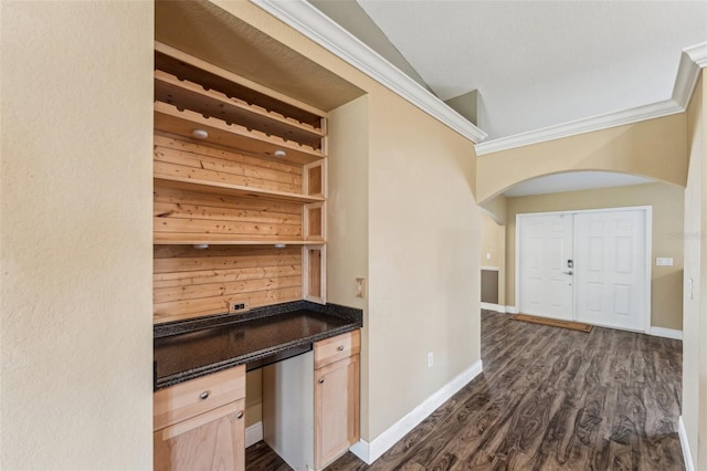 bar with dark wood-type flooring, lofted ceiling, built in desk, light brown cabinets, and ornamental molding