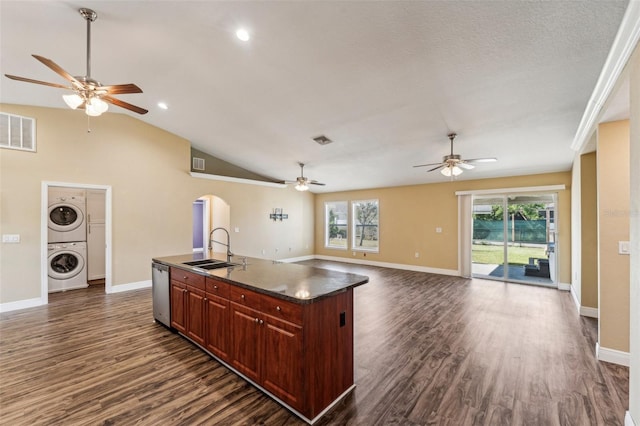 kitchen with dark hardwood / wood-style floors, an island with sink, sink, stacked washer / drying machine, and stainless steel dishwasher