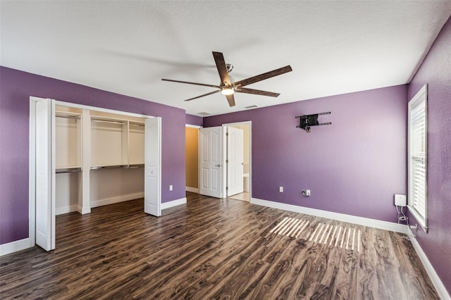 unfurnished bedroom with dark wood-type flooring, ceiling fan, and a closet