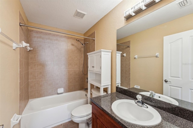 full bathroom with vanity, toilet, tiled shower / bath combo, and a textured ceiling