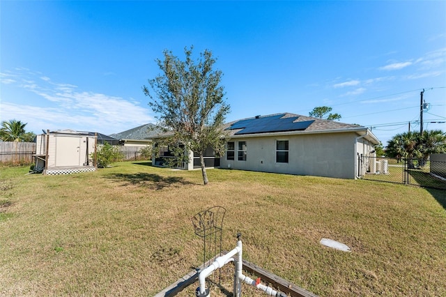 back of property with a storage shed, a yard, and solar panels