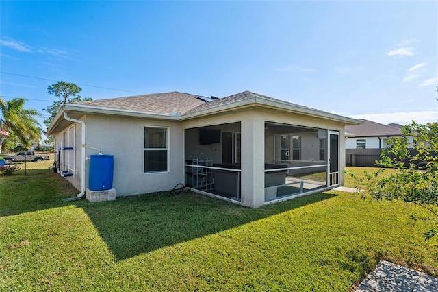 rear view of house featuring a lawn and a sunroom