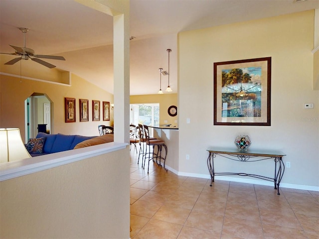 hall featuring light tile patterned flooring and vaulted ceiling