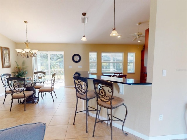 kitchen with a kitchen bar, decorative light fixtures, vaulted ceiling, light tile patterned floors, and kitchen peninsula