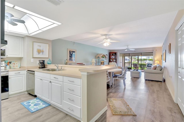 kitchen featuring sink, white cabinetry, a skylight, light hardwood / wood-style floors, and kitchen peninsula