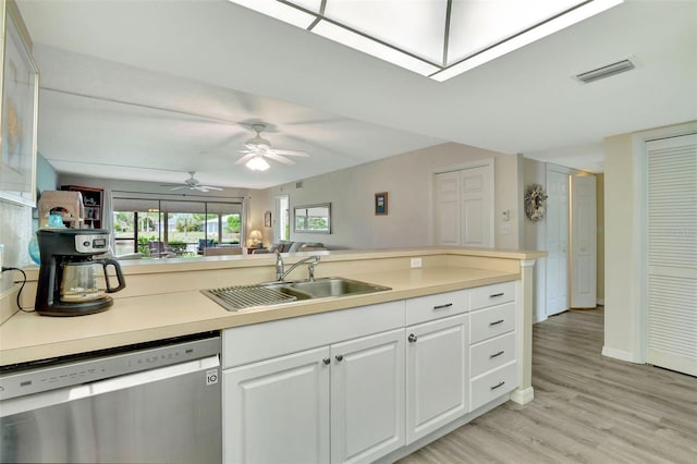 kitchen featuring sink, light wood-type flooring, white cabinetry, dishwasher, and a skylight